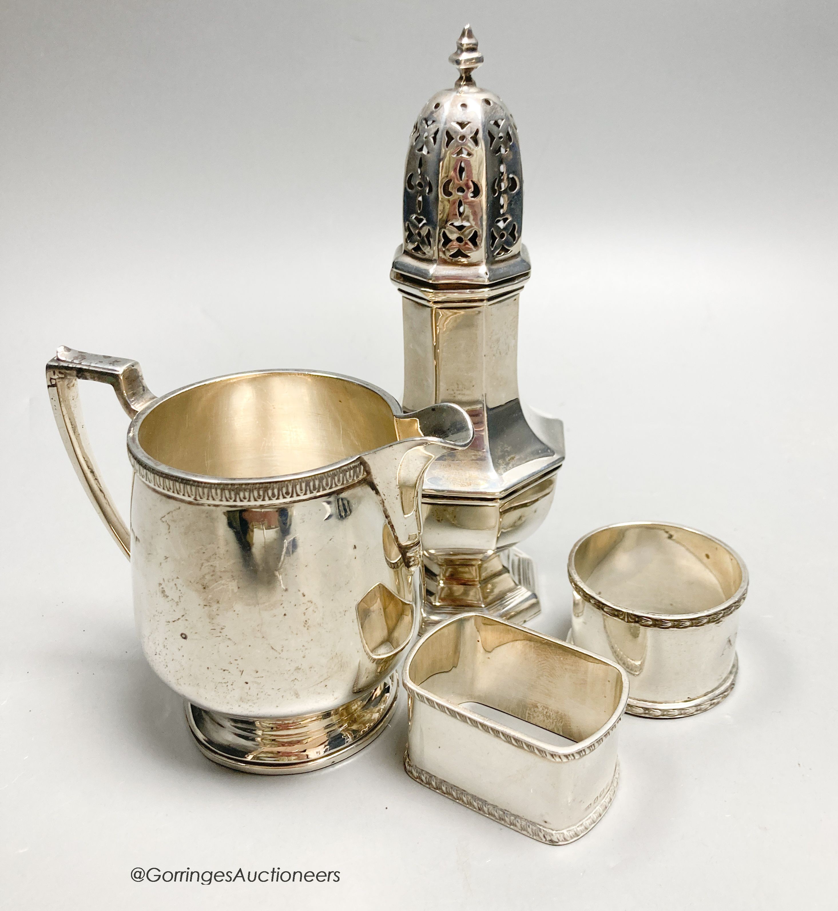 A George V silver jug, Birmingham, 1928, a silver caster and two silver napkin rings, 10oz.